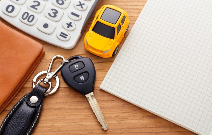 Car key with notebook calculator and pocket money on wood table